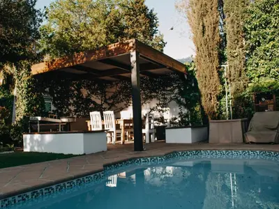 a pool with a pergola and a table and chairs at Cummings Guesthouse in Wellington