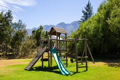 a playground with a slide in the grass at Steenbok Farm Cottages Steenbok cottage in Wolseley