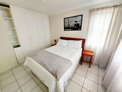 a bedroom with a large white bed and a window at Broadway Self Catering Apartments in Durbanville