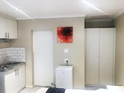 a kitchen with white cabinets and a red painting on the wall at Selton Guesthouse in Cape Town