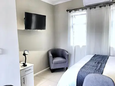 a bedroom with a bed and a chair and a tv at Selton Guesthouse in Cape Town