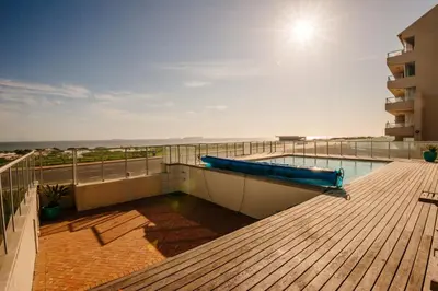 a balcony with a swimming pool on top of a building at Voir la Mer - Blouberg Beach in Bloubergstrand