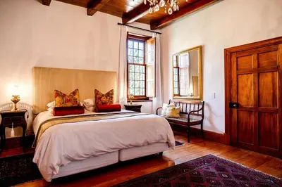 a bedroom with a large bed with red pillows at Cape Dutch @ Keerweder in Franschhoek