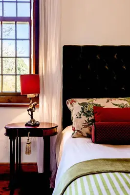 a bedroom with a bed and a red lamp on a table at Cape Dutch @ Keerweder in Franschhoek