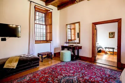 a bedroom with a bed and a table and a rug at Cape Dutch @ Keerweder in Franschhoek