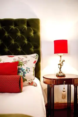 a bedroom with a bed with a red lamp on a table at Cape Dutch @ Keerweder in Franschhoek