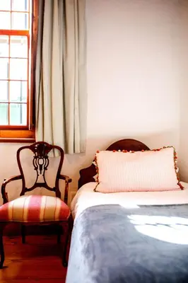 a bedroom with a bed and a chair and a window at Cape Dutch @ Keerweder in Franschhoek