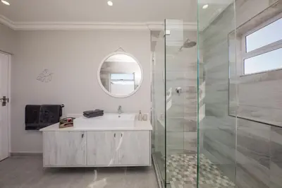 a bathroom with a sink and a glass shower at The Little Palm in Bloubergstrand