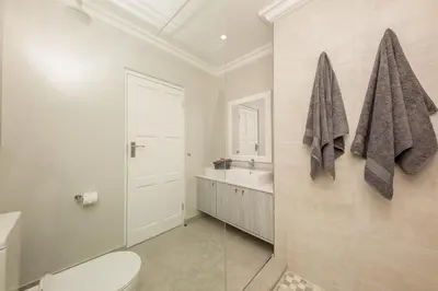 a white bathroom with a toilet and a sink at The Little Palm in Bloubergstrand