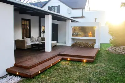 a deck with a fireplace in the backyard of a house at Langbaai Beach Cottage in Hermanus