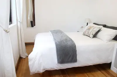a bedroom with a white bed with a gray blanket at Langbaai Beach Cottage in Hermanus