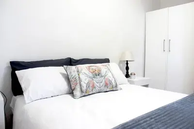 a white bed with two pillows on top of it at Langbaai Beach Cottage in Hermanus