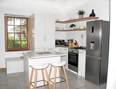a kitchen with a stainless steel refrigerator and stools at Langbaai Beach Cottage in Hermanus