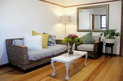 a living room with a couch and a table and a mirror at Langbaai Beach Cottage in Hermanus