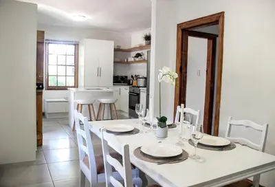a kitchen and dining room with a white table and chairs at Langbaai Beach Cottage in Hermanus