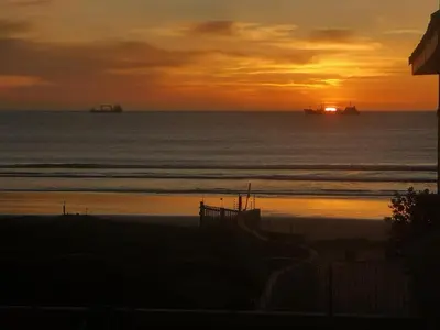 a sunset over the ocean with ships in the water at Lagoon Beach Neptune Isle Cape Town in Cape Town