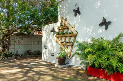 a garden shelf with butterflies on the side of a building at Angel's Corner in Cape Town