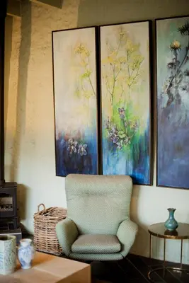 a chair in a room with four paintings on the wall at Bosjes - Herehuis in Breerivier