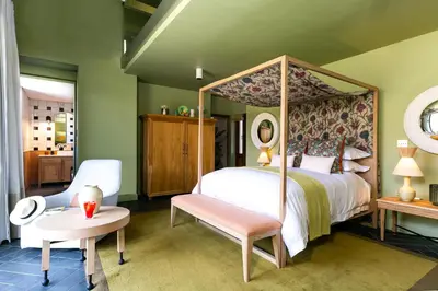 a bedroom with a canopy bed with a chair and a table at Bosjes - Herehuis in Breerivier