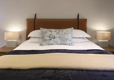 a bed with a pillow on it with two lamps at Stony Brook Cottages in Franschhoek
