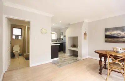 a living room with a table and a kitchen at Stony Brook Cottages in Franschhoek