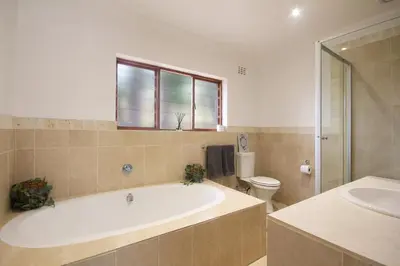 a bathroom with a tub and a toilet and a sink at Stony Brook Cottages in Franschhoek