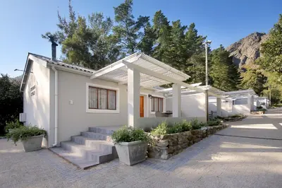 a small white house with stairs and trees at Stony Brook Cottages in Franschhoek