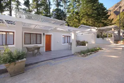a white house with a patio with a table at Stony Brook Cottages in Franschhoek