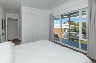 a white bedroom with a large bed and a large window at Views Views Views in Hermanus