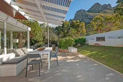 a patio with a white table and chairs and a hill at Views Views Views in Hermanus