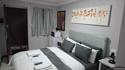 a bedroom with a bed with white sheets and pillows at Robert's Place Paarl in Paarl