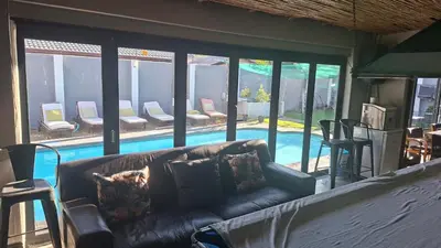 a living room with a couch and a swimming pool at Robert's Place Paarl in Paarl