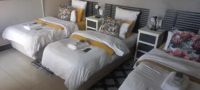 a room with three beds with white sheets at Robert's Place Paarl in Paarl