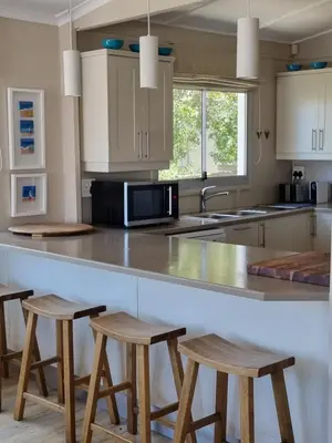 a kitchen with a counter and stools in it at Potluck Cottage in Hermanus
