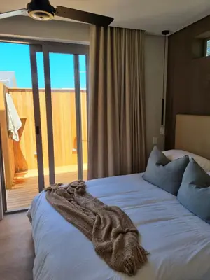 a bedroom with a bed with a blanket on it at Potluck Cottage in Hermanus