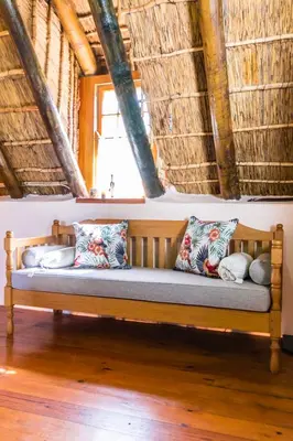 a wooden bench sitting in a room with pillows at Die Wasbak in Greyton