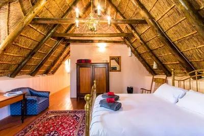 a bedroom with a bed and a chair in a room at Die Wasbak in Greyton