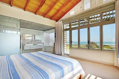 a bedroom with a bed and a view of the ocean at Atlantic Blue Villa at Pilots in Cape Town