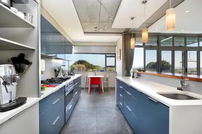 a large kitchen with blue cabinets and a table at Atlantic Blue Villa at Pilots in Cape Town