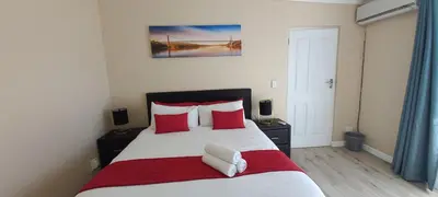 a bedroom with a large bed with red and white pillows at Arlogenix in Durbanville