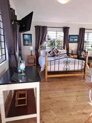 a bedroom with a bed and a table at Whale Tale near Kite Beach in Cape Town