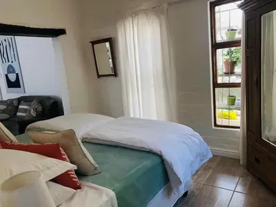 a bedroom with two beds and a window at The Lily House Hermanus in Hermanus