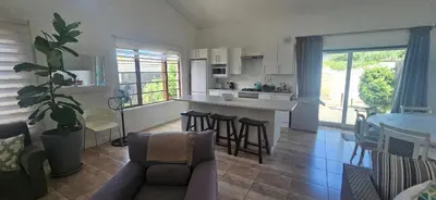 a kitchen and living room with a couch and a table at The Lily House Hermanus in Hermanus