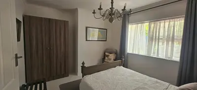 a bedroom with a bed and a window and a chandelier at The Lily House Hermanus in Hermanus