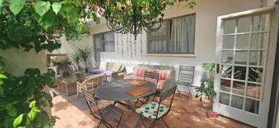 a patio with a table and chairs and a couch at The Lily House Hermanus in Hermanus