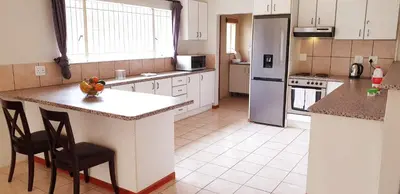 a kitchen with white cabinets and a island with a counter top at Riverside Villa in Gordonʼs Bay