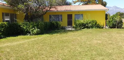 a yellow house with a yard in front of it at Riverside Villa in Gordonʼs Bay