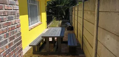 a wooden bench sitting next to a yellow wall at Riverside Villa in Gordonʼs Bay