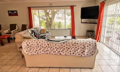 a living room with a couch and a flat screen tv at Riverside Villa in Gordonʼs Bay