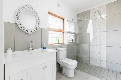 a bathroom with a toilet and a sink and a mirror at Cornerstone Guesthouse Alk Van Zyl in Panorama